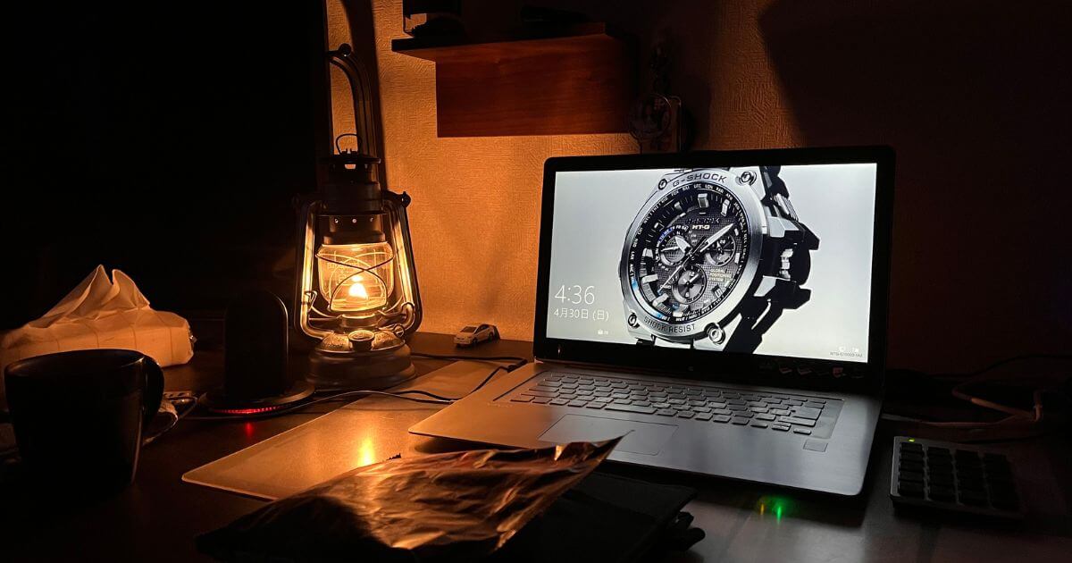 ランタンの明かりに照らされた暗い部屋で、G-SHOCKの時計がノートパソコンの画面に表示されている。